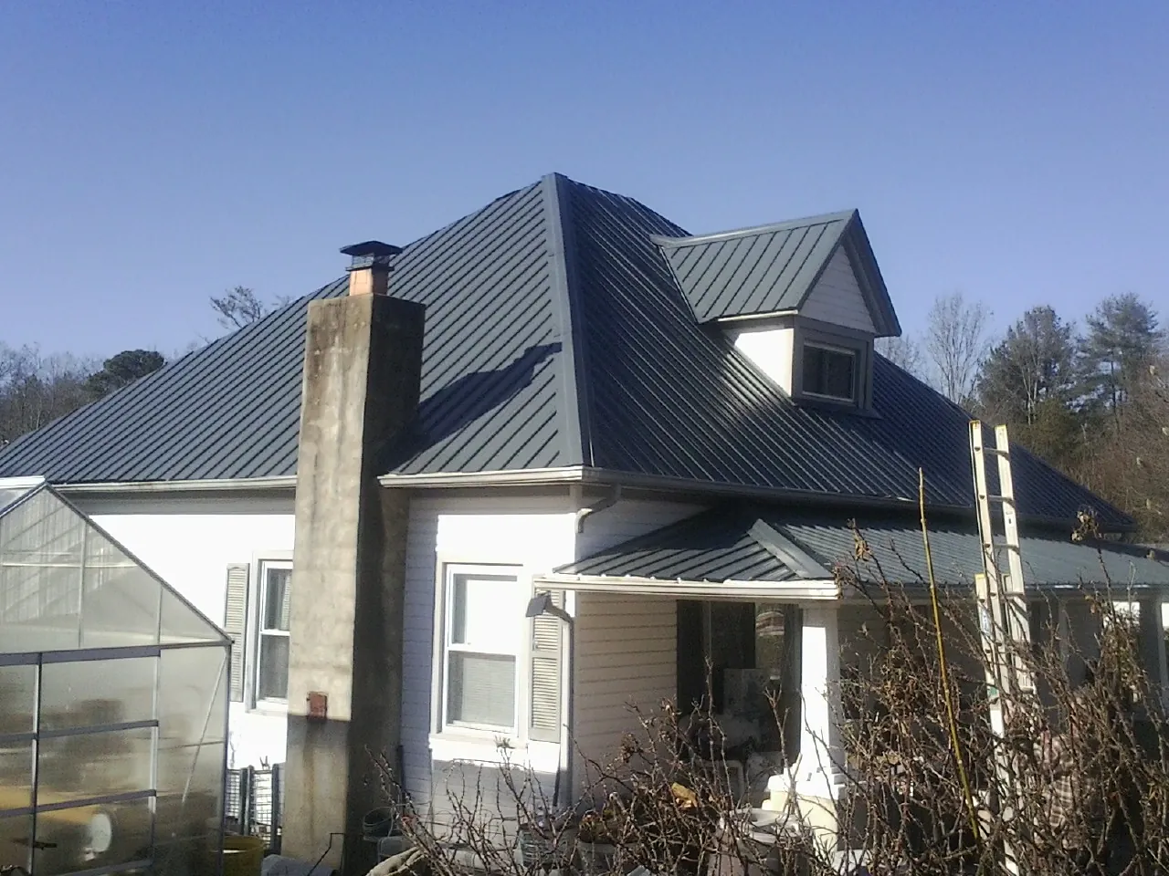 Dark blue standing seam metal roof on a white farmhouse with dormer — Slate & Tile Roof Repair by Roofing Brothers in Roseland