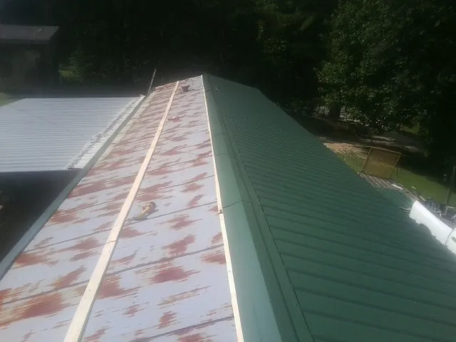 Old rusted panels beside newly installed green metal roofing — Wind Damage Roof Repair by Roofing Brothers in Roseland