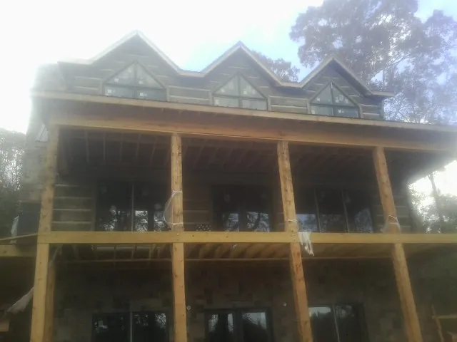 Dormers and porch framing on a large log home under construction — Roof Coating work by our crew in Roseland