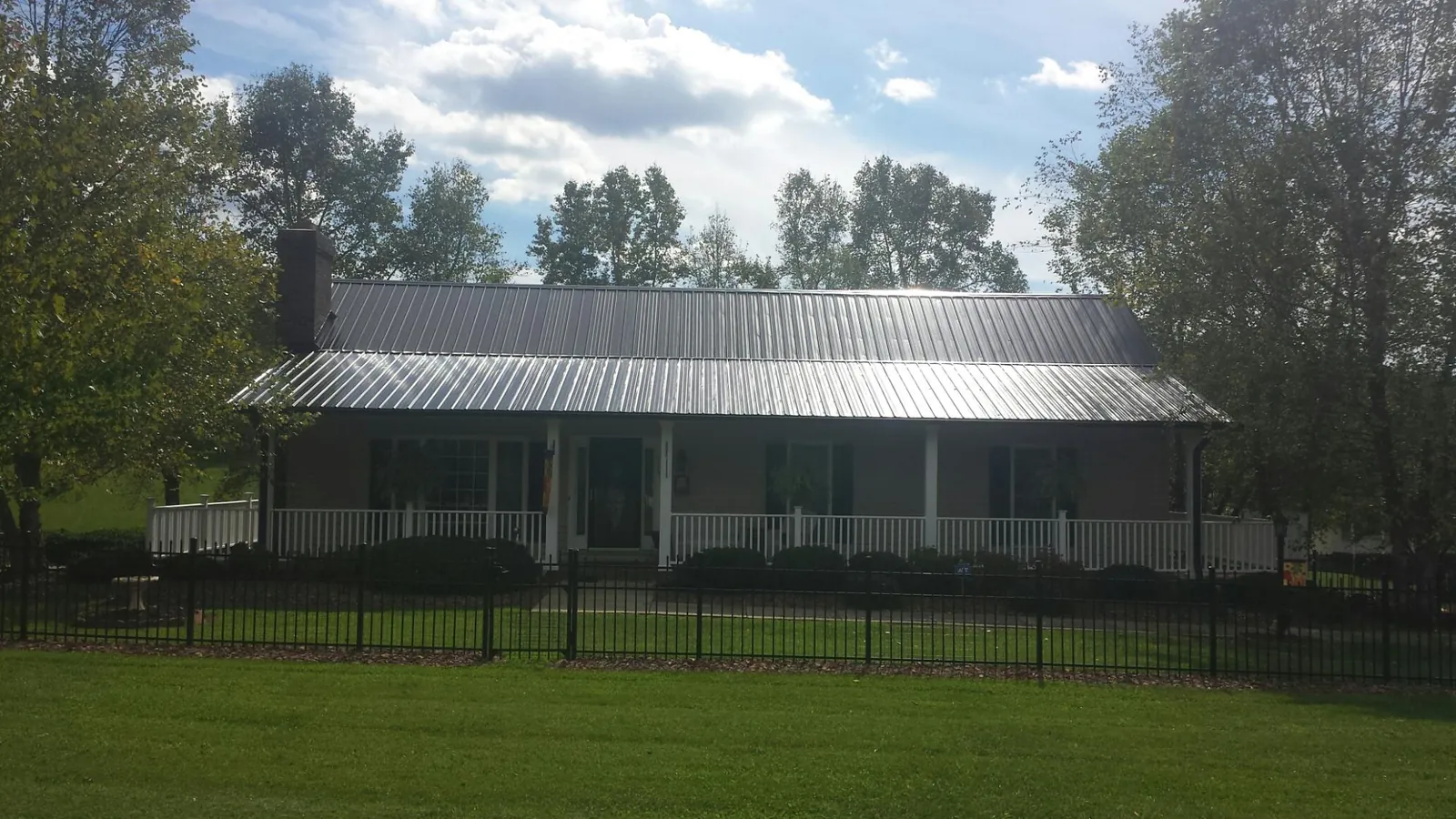 Gray metal roof on a brick ranch with a full width front porch — Gutter Guard Installation work by our crew in Roseland