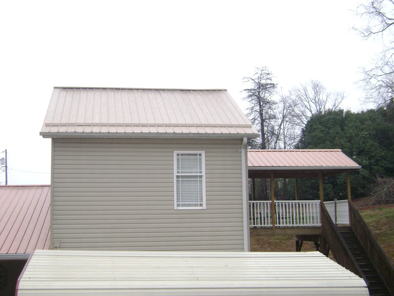 Tan metal roofs on a two story addition and attached porch, from a Roof Replacement job in Roseland