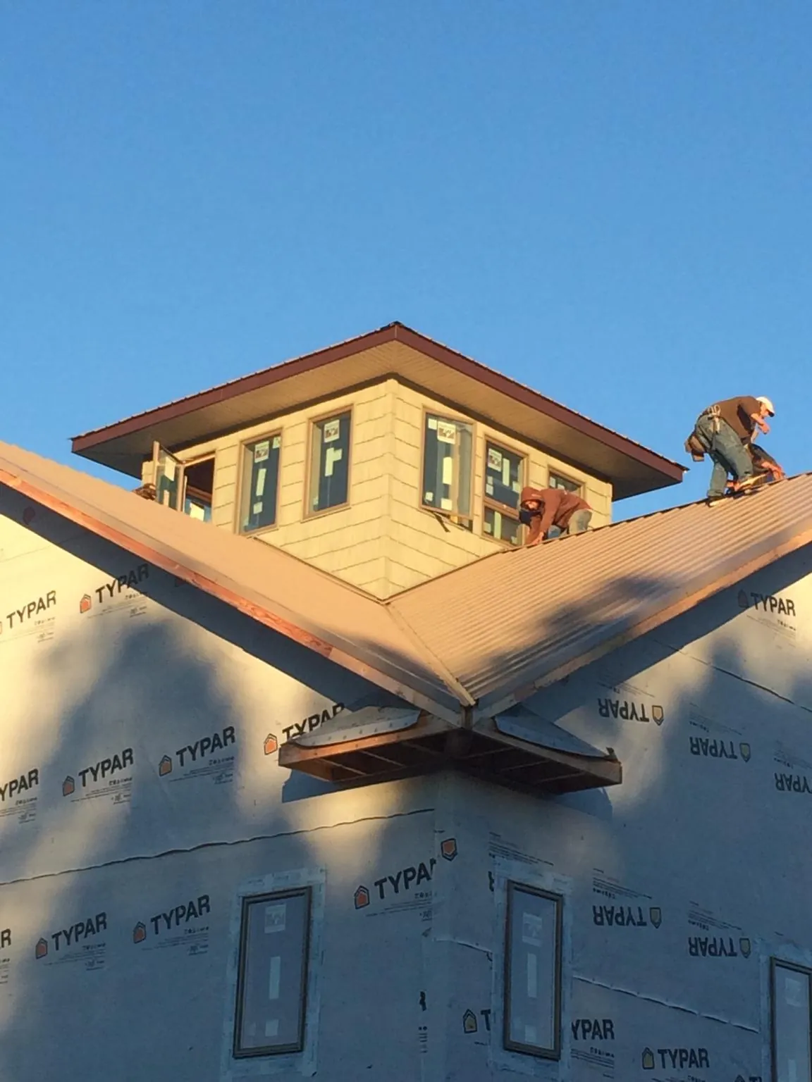 Roofers working around a rooftop cupola on a new metal roof at sunset — Roof Waterproofing in Roseland by Roofing Brothers